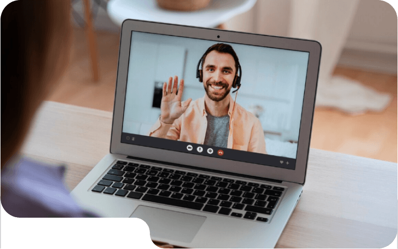 Smiling man in a blue shirt on a video call displayed on a laptop screen with call control icons below.