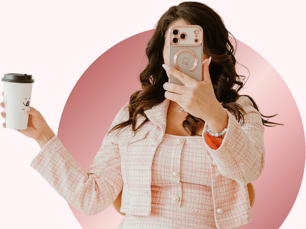 Natalie McElwain taking a photo with her phone while holding a coffee