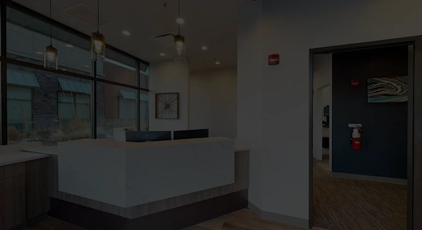 Modern office reception area with white marble desk, large windows, and pendant lights.