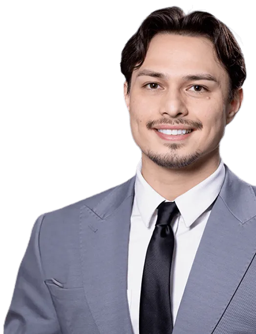 Smiling Dr Barry with short dark hair, wearing a gray suit, white shirt, and black tie.