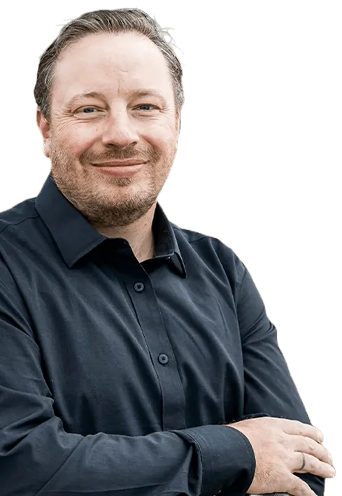Smiling Dr Paylor with short hair and beard wearing a dark button-up shirt, arms crossed.