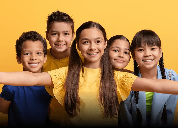 Young woman with long brown hair winking and smiling while taking a selfie outdoors, holding up a peace sign.
