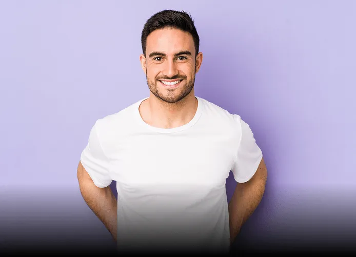 Young woman with long brown hair winking and smiling while taking a selfie outdoors, holding up a peace sign.