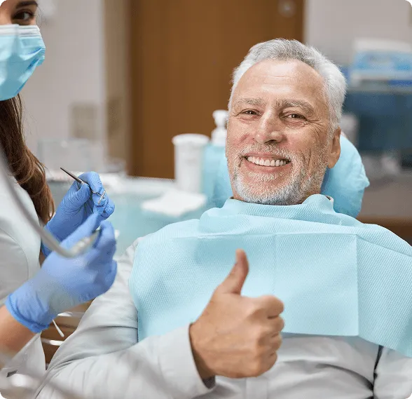 Smiling woman reclined in a dental chair, interacting with a dentist wearing blue gloves.