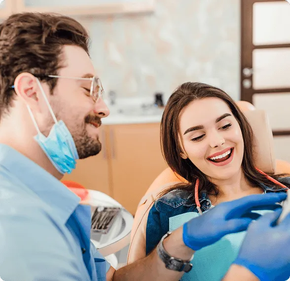 Smiling woman sitting in a dental chair giving a thumbs-up with a dental bib.
