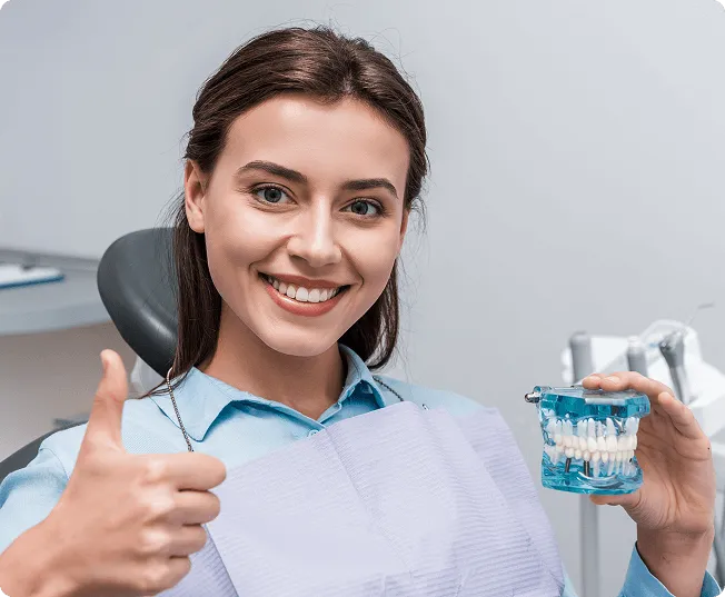 Smiling man sitting in a dental chair giving a thumbs-up in a bright dental office.