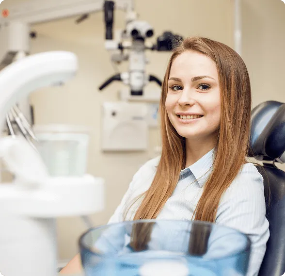 Smiling woman reclined in a dental chair, interacting with a dentist wearing blue gloves.