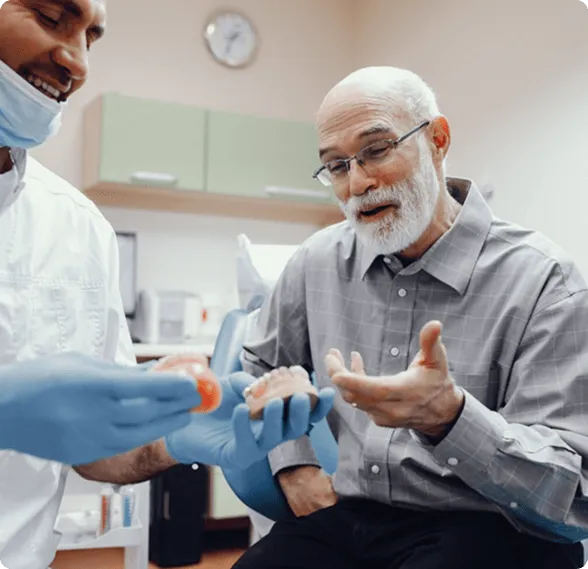 Modern dental examination room with a black and white dental chair, dental equipment, a large mirror on gray wall, and a mounted TV screen.