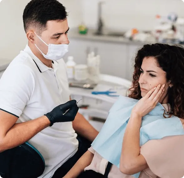 Dentist holding a dental shade guide near a smiling woman's teeth to match tooth color.