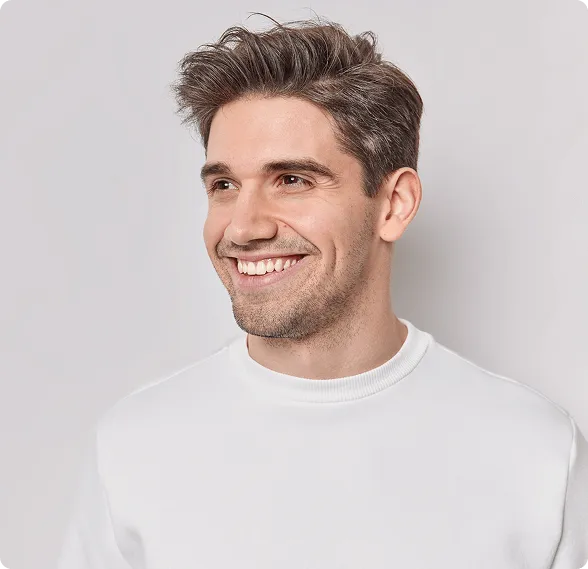 Modern dental examination room with a black and white dental chair, dental equipment, a large mirror on gray wall, and a mounted TV screen.