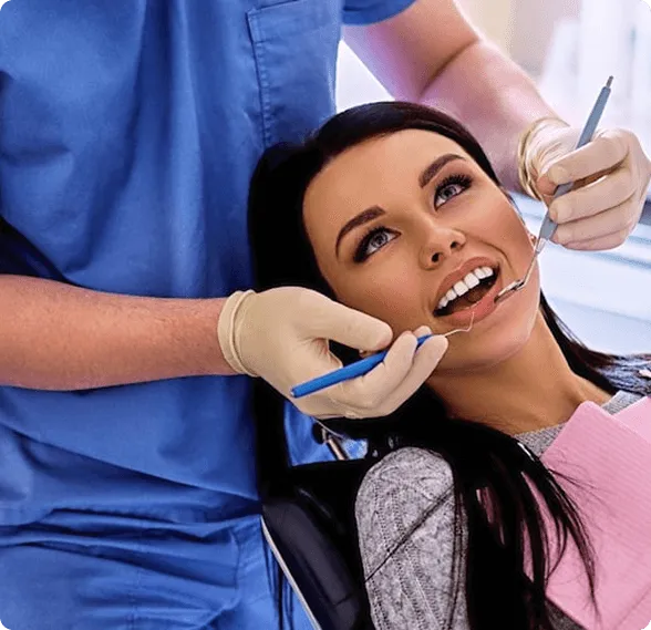 Dentist holding a dental shade guide near a smiling woman's teeth to match tooth color.