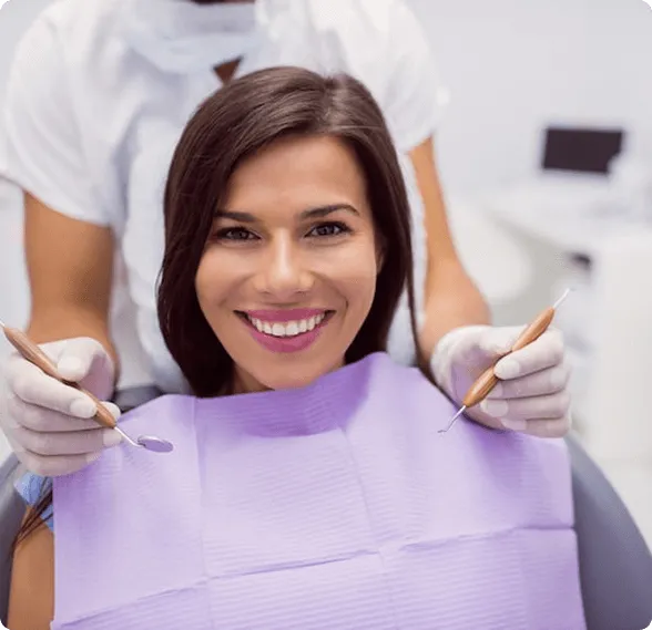 Smiling man sitting in a dental chair giving a thumbs-up in a bright dental office.