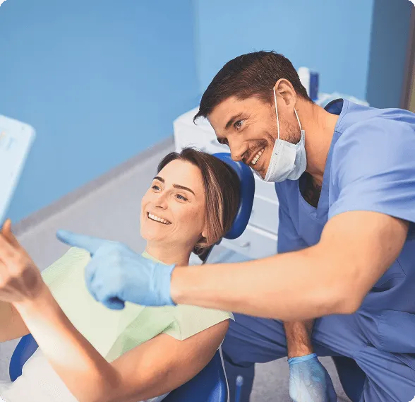 Dentist holding a dental shade guide near a smiling woman's teeth to match tooth color.