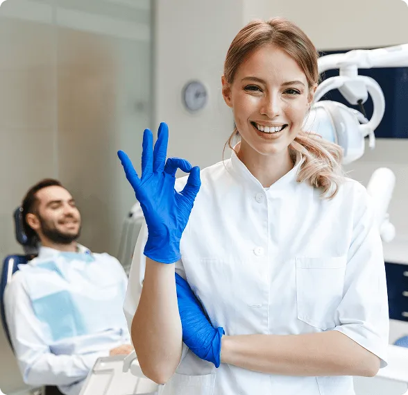 Smiling man sitting in a dental chair giving a thumbs-up in a bright dental office.