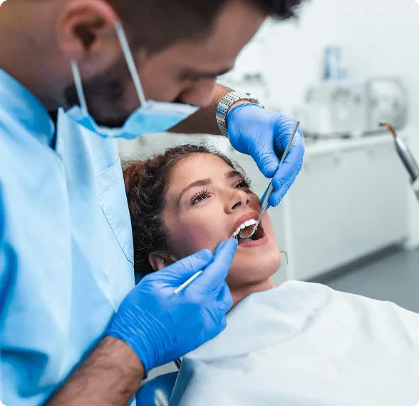 Smiling woman reclined in a dental chair, interacting with a dentist wearing blue gloves.