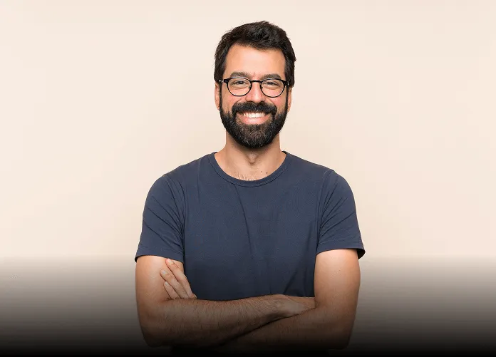 Young woman with long brown hair winking and smiling while taking a selfie outdoors, holding up a peace sign.