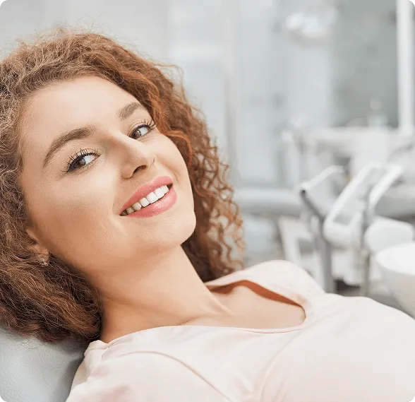 Dentist holding a dental shade guide near a smiling woman's teeth to match tooth color.