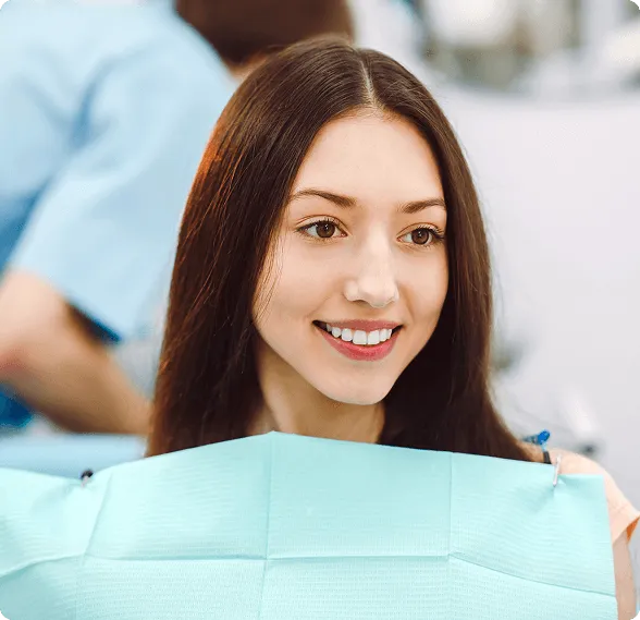 Dentist holding a dental shade guide near a smiling woman's teeth to match tooth color.