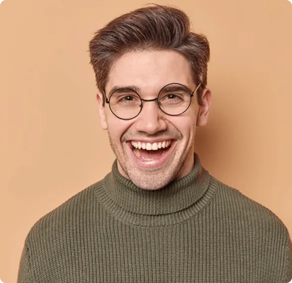 Smiling man sitting in a dental chair giving a thumbs-up in a bright dental office.