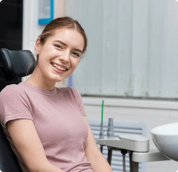 Modern dental examination room with a black and white dental chair, dental equipment, a large mirror on gray wall, and a mounted TV screen.