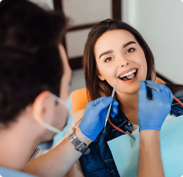 Smiling man sitting in a dental chair giving a thumbs-up in a bright dental office.