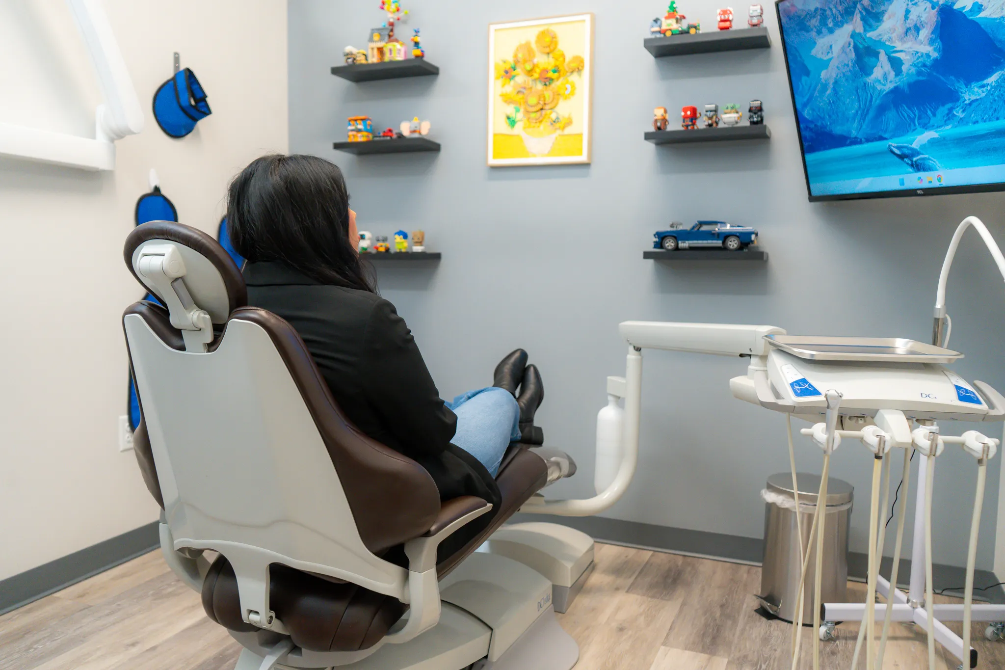 Smiling man sitting in a dental chair giving a thumbs-up in a bright dental office.
