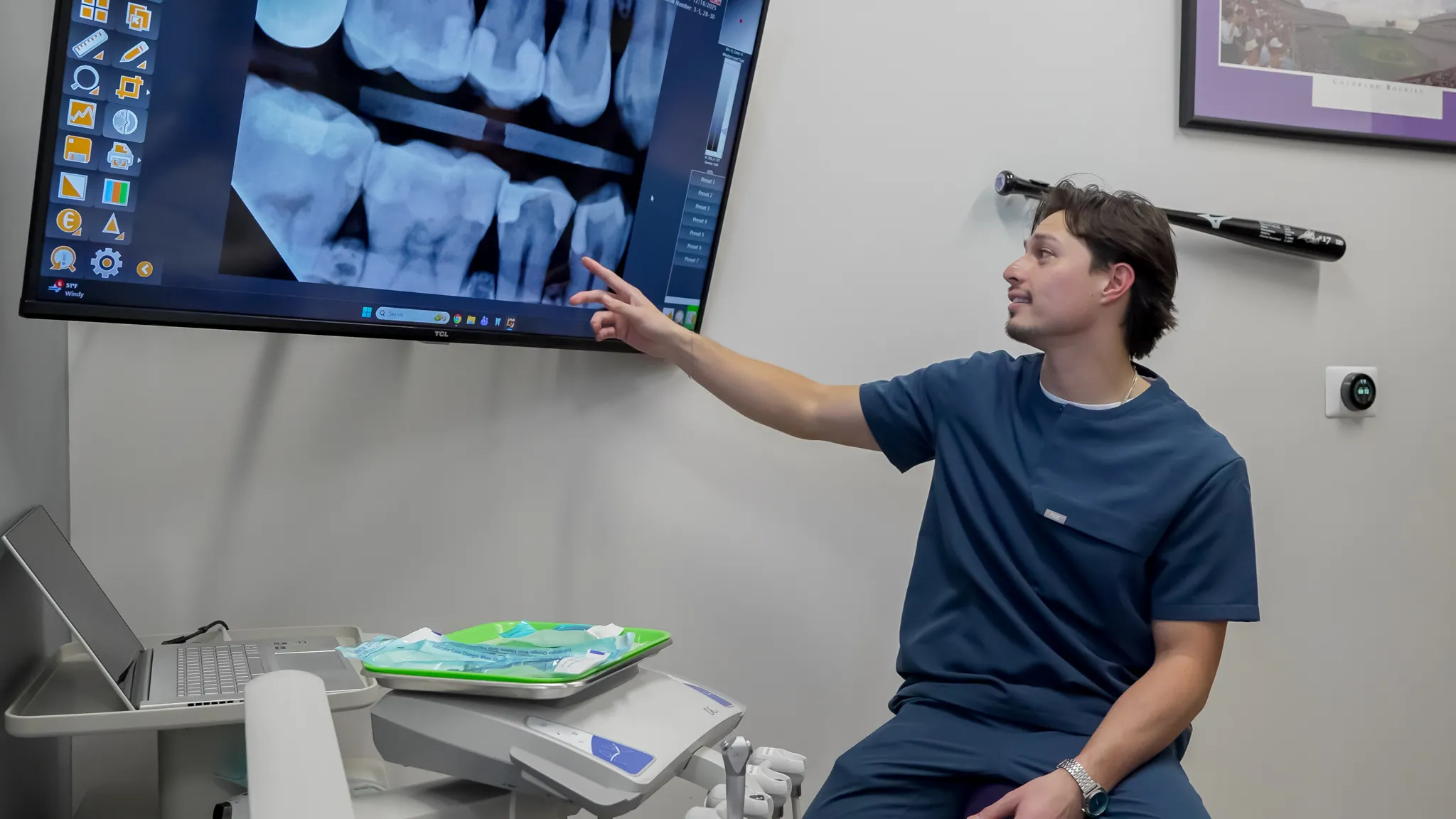 Smiling man sitting in a dental chair giving a thumbs-up in a bright dental office.