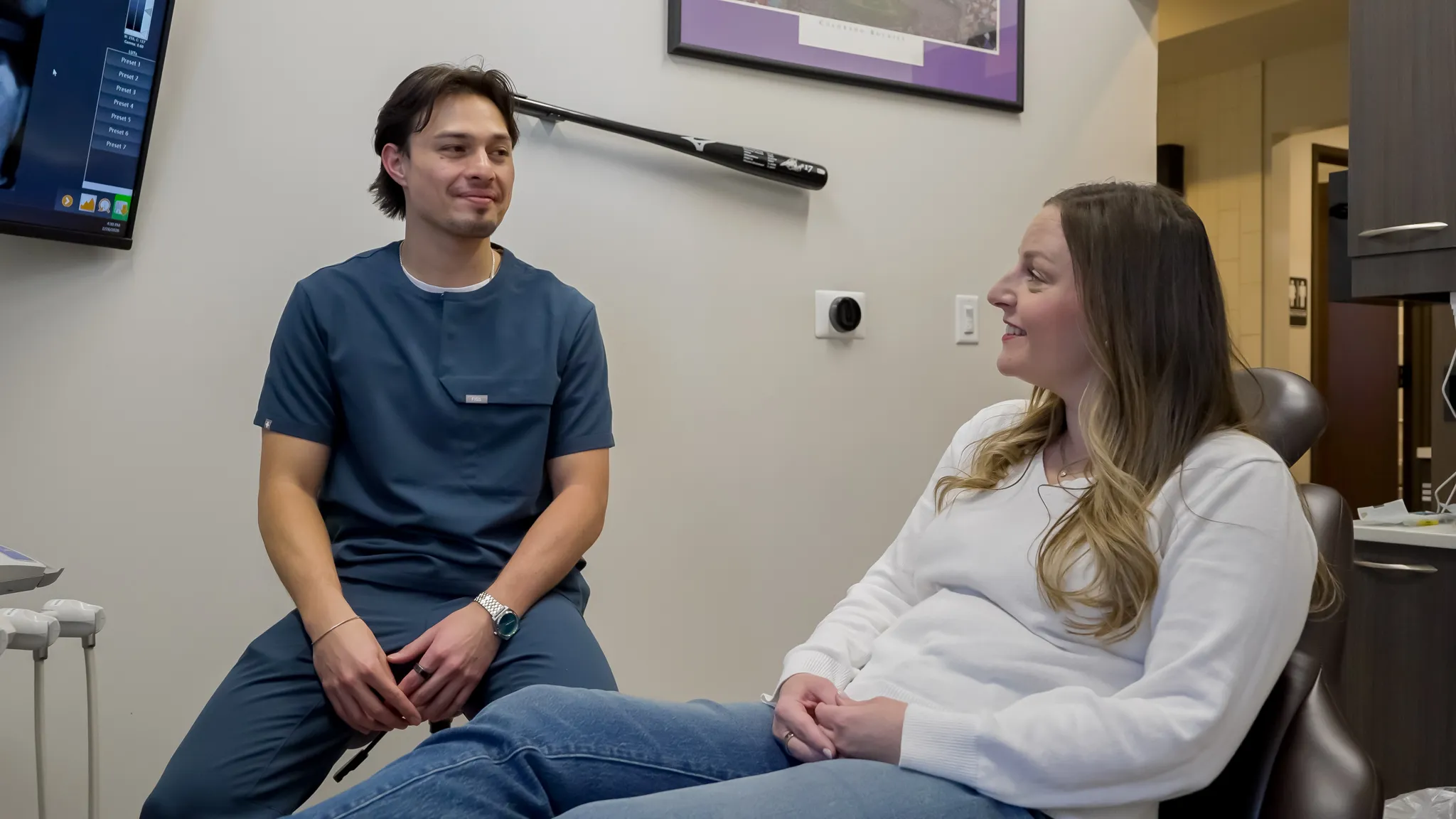 Dentist holding a dental shade guide near a smiling woman's teeth to match tooth color.