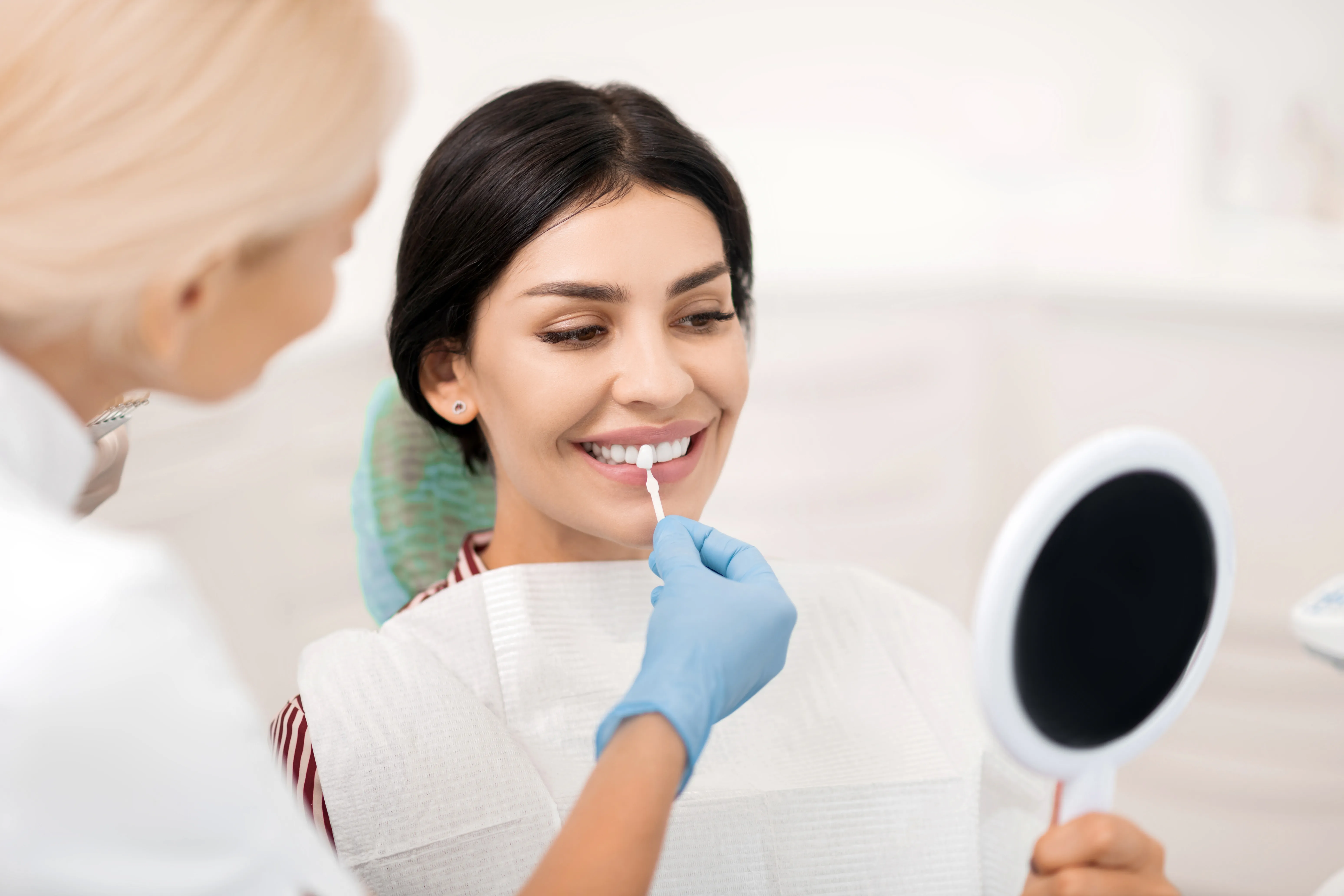 Smiling man sitting in a dental chair giving a thumbs-up in a bright dental office.