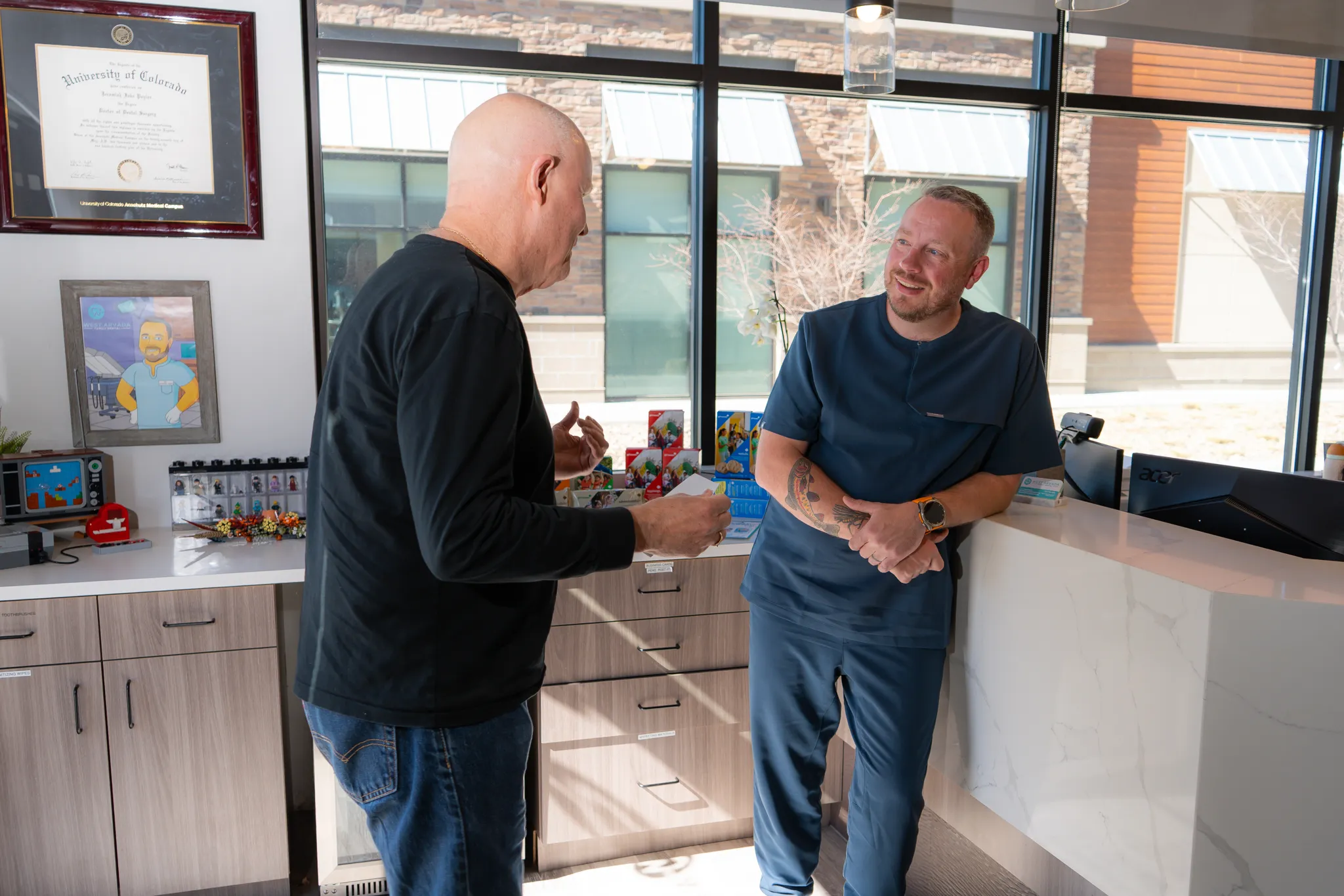 Smiling man sitting in a dental chair giving a thumbs-up in a bright dental office.