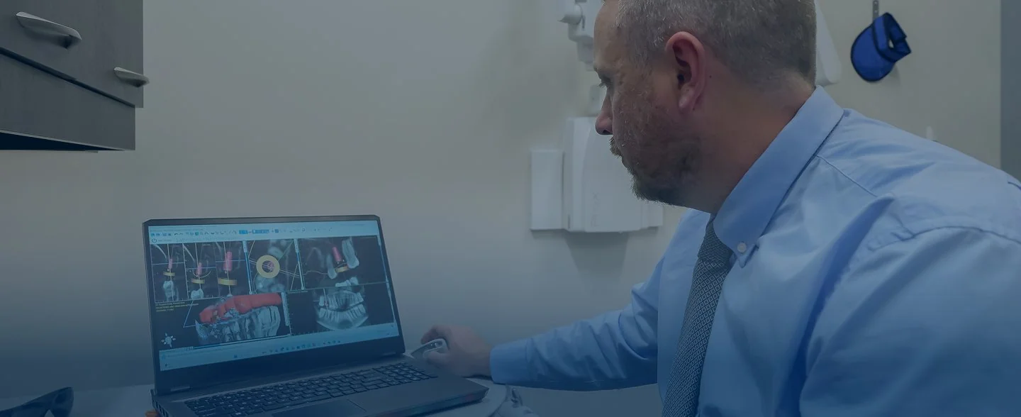 Modern reception desk with marble countertop, two computer monitors, pendant lights, and large windows showing exterior building.