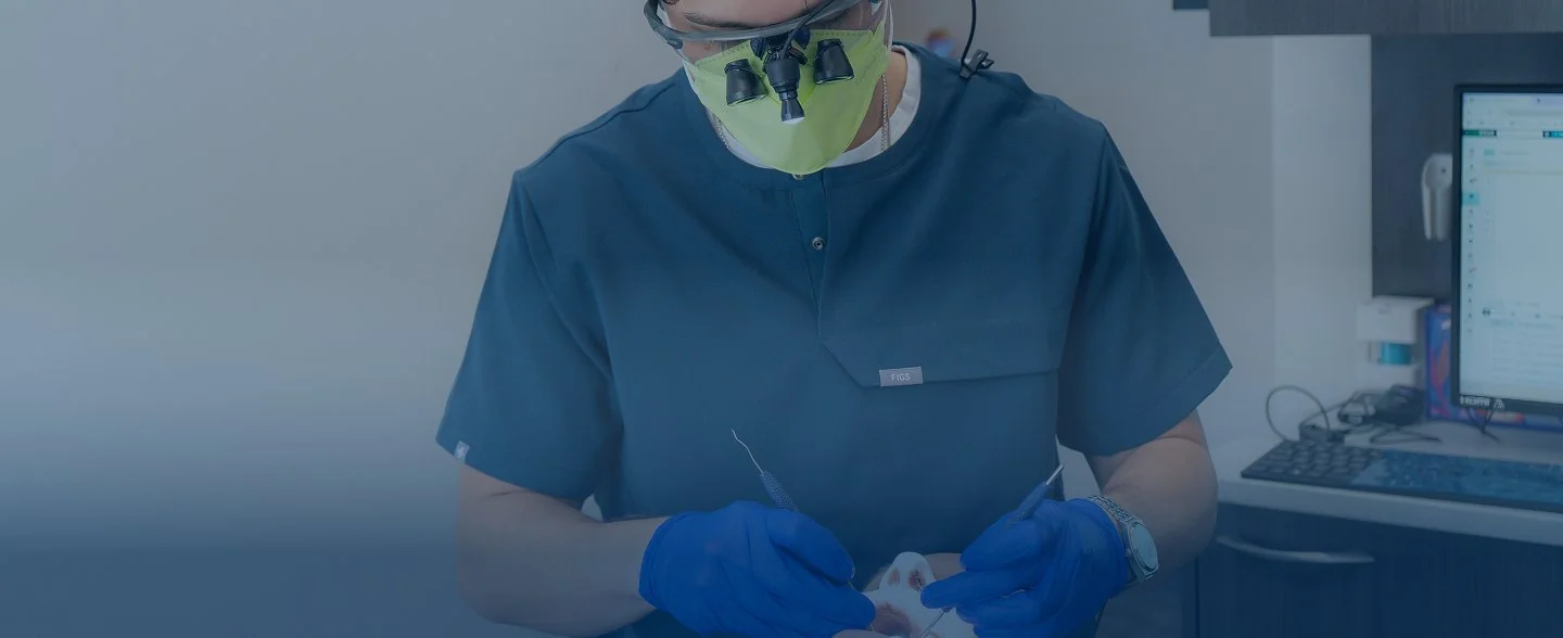 Modern reception desk with marble countertop, two computer monitors, pendant lights, and large windows showing exterior building.