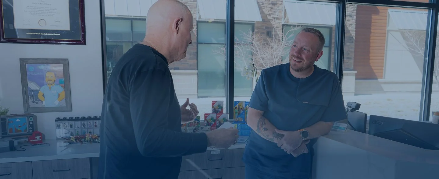 Modern reception desk with marble countertop, two computer monitors, pendant lights, and large windows showing exterior building.