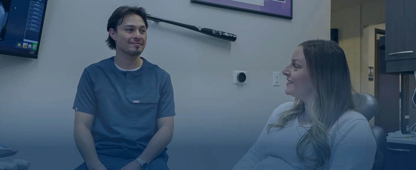 Modern reception desk with marble countertop, two computer monitors, pendant lights, and large windows showing exterior building.