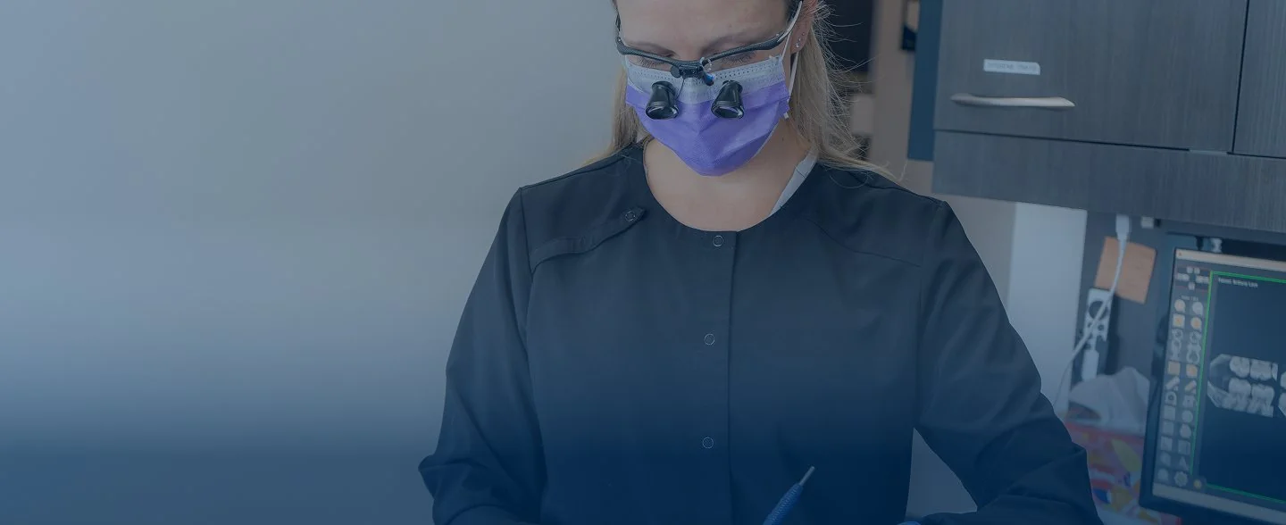 Modern reception desk with marble countertop, two computer monitors, pendant lights, and large windows showing exterior building.