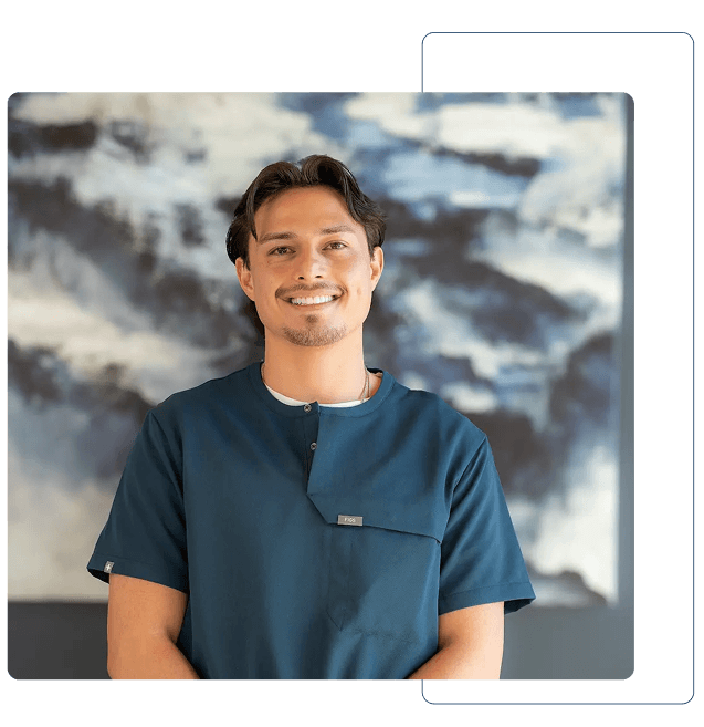 Dentist holding a dental shade guide near a smiling woman's teeth to match tooth color.