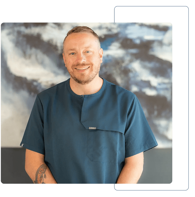 Dentist holding a dental shade guide near a smiling woman's teeth to match tooth color.