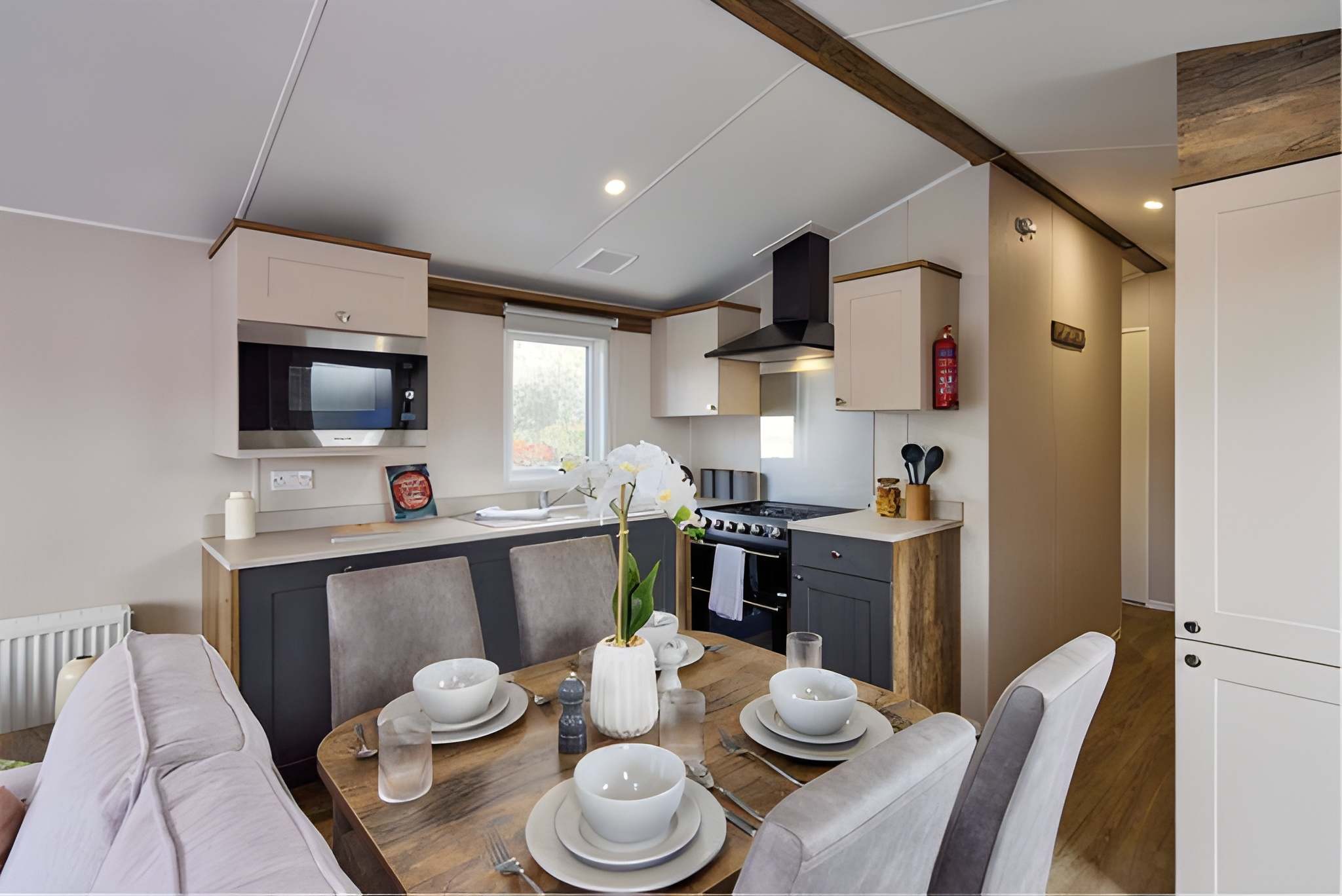 Modern kitchen and dining area with wooden table and white place settings