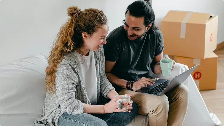 Couple sitting on couch talking with a laptop on lap