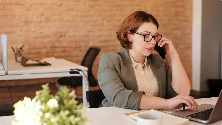 Lady sitting at her desk on her laptop and talking on the phone