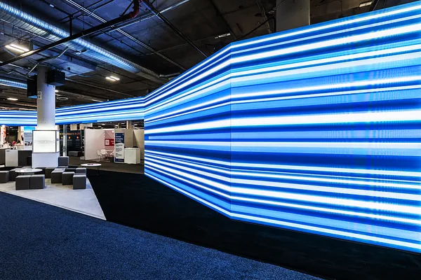 Angled LED wall wrapping a trade show booth with blue motion graphics at CES