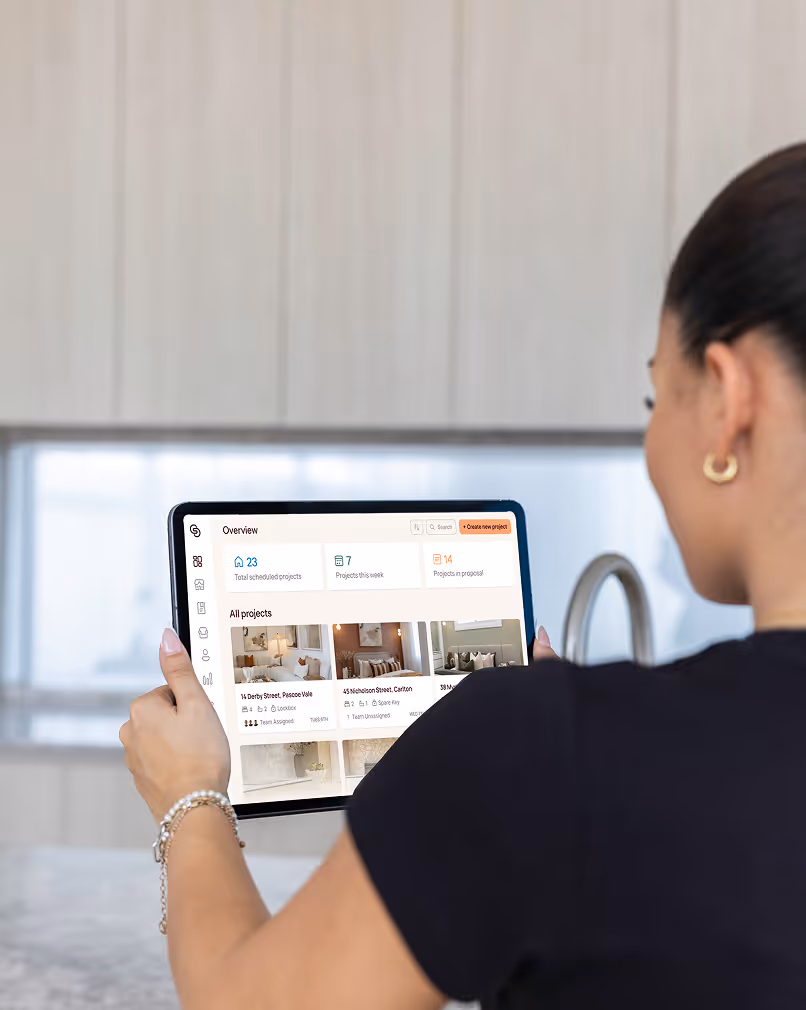 Person holding a tablet displaying a project management dashboard with project summaries and images.