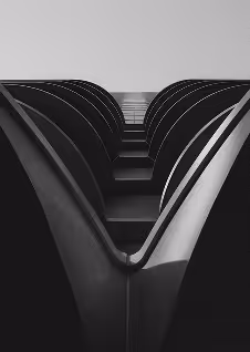 Black and white photo looking upward between two symmetrical curved architectural structures.