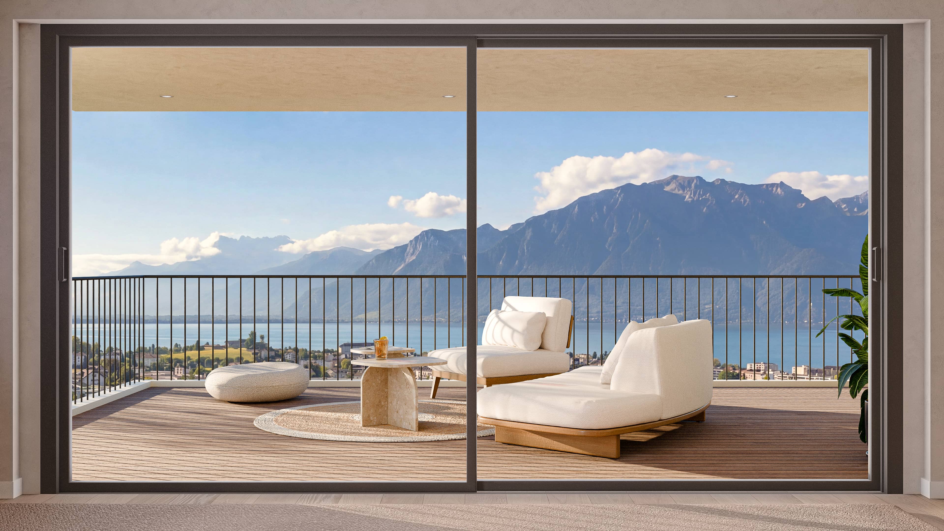 Balcon moderne avec des chaises longues rembourrées blanches, un tapis rond, une petite table avec une boisson et une vue panoramique sur les montagnes et un lac.