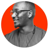 Profile of a smiling man wearing glasses and a necklace against a bright red circular background.