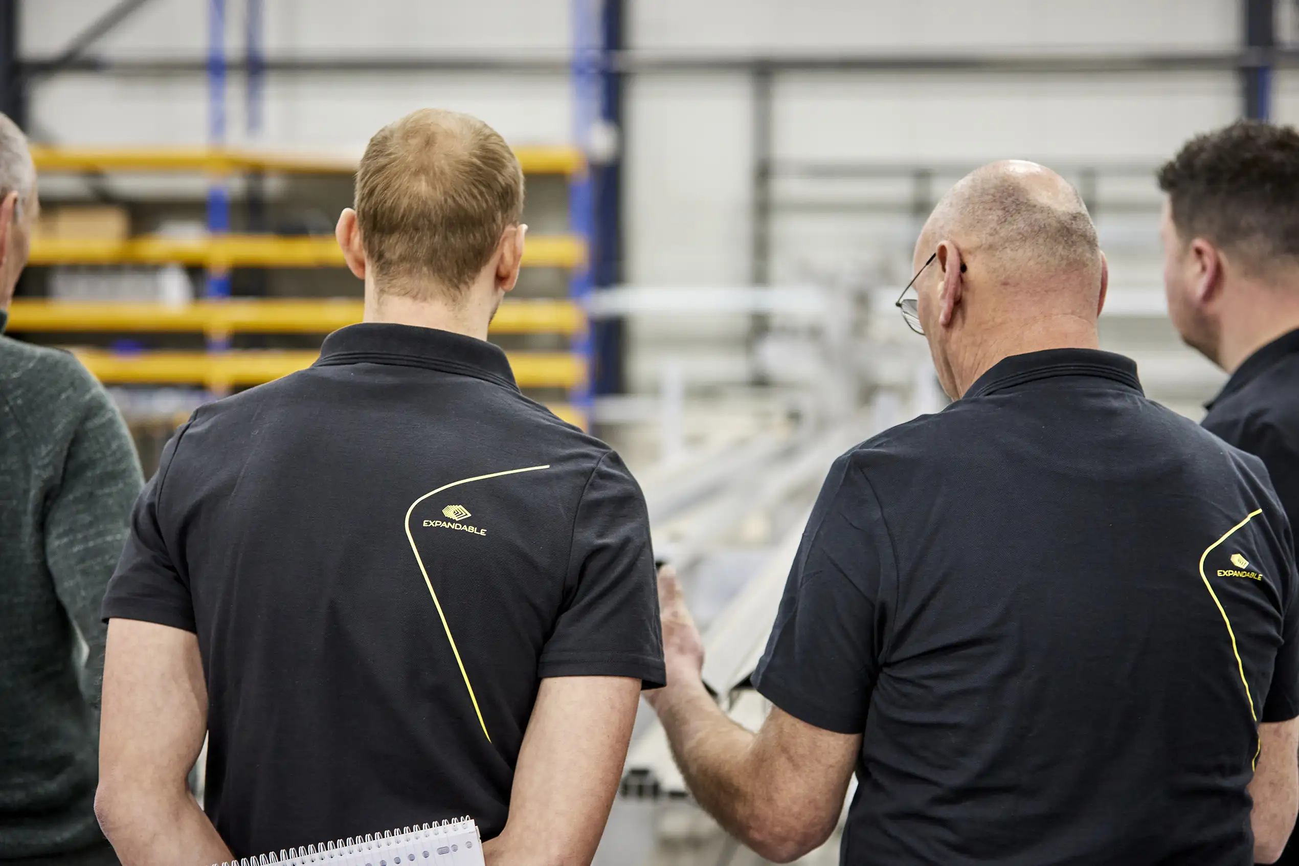 Expandable team members in discussion over production details, exemplifying teamwork and focus on precision in creating modular movable spaces.