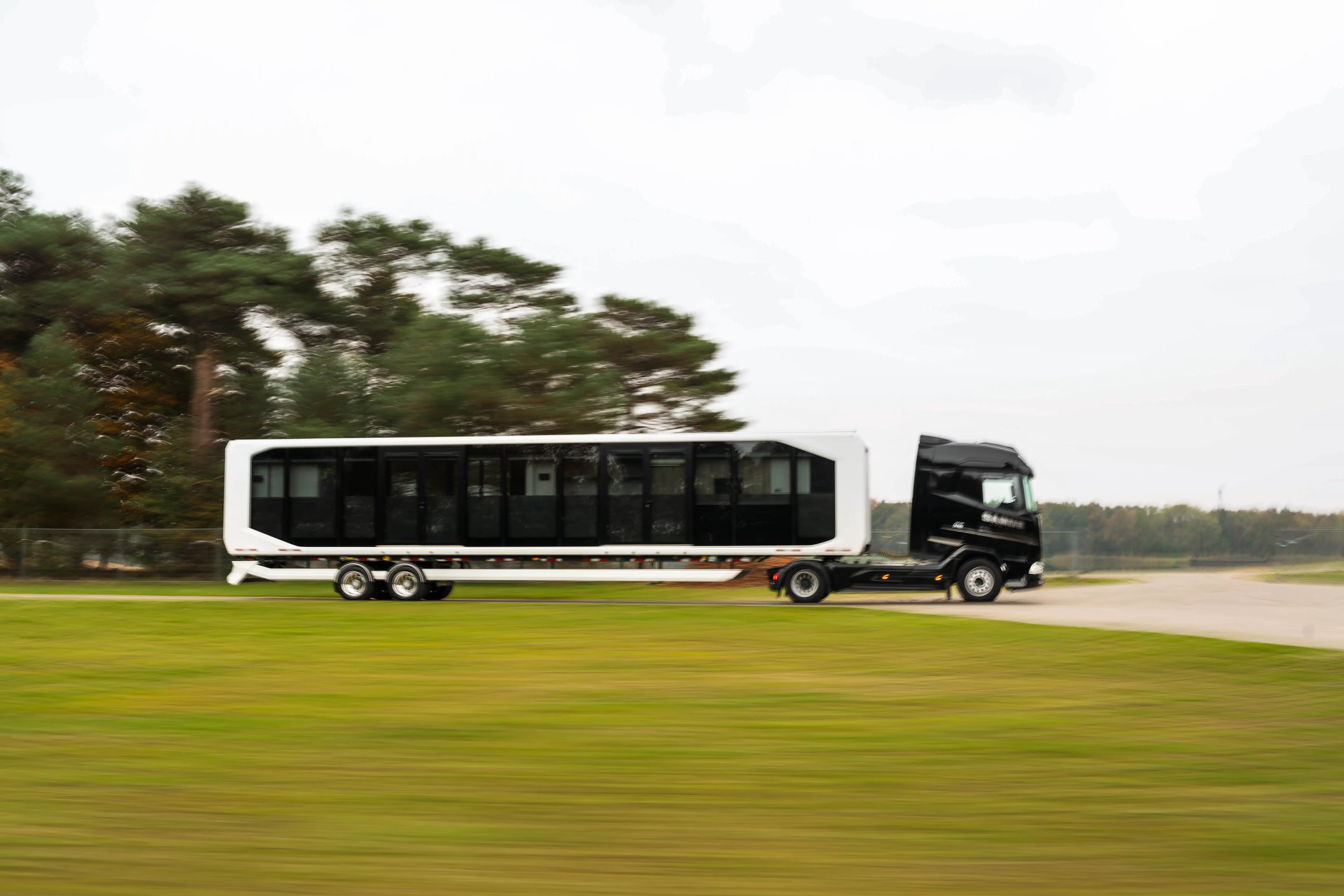 Expandable relocatable space unit in transit, towed by a black truck, demonstrating mobility and rapid deployment capabilities on the road