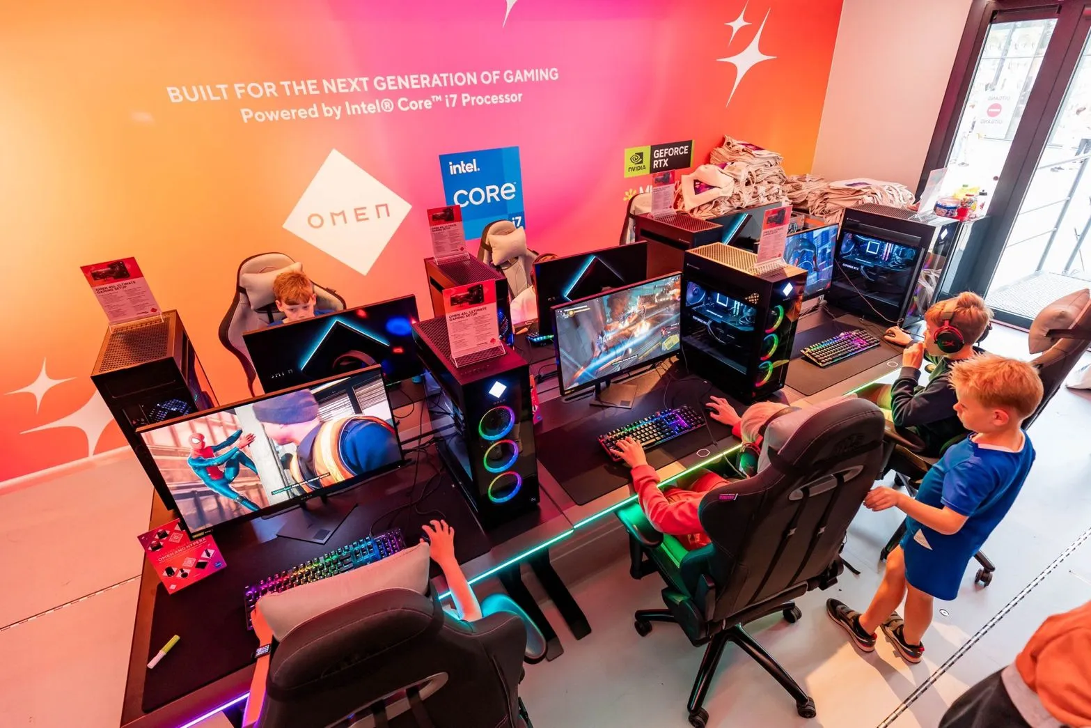 Children enjoying interactive video games inside a vibrant mobile gaming trailer, equipped with ergonomic gaming chairs and high-end gaming PCs featuring colorful LED lighting.