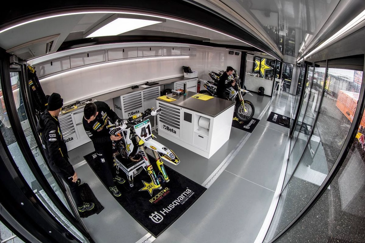 Un espace mobile Expandable élégant et moderne présentant un intérieur entièrement équipé avec une zone d'entretien des motos, y compris des stations d'outils et des vélos, reflétant la technologie de pointe et le design multifonctionnel idéal pour les équipes de course.