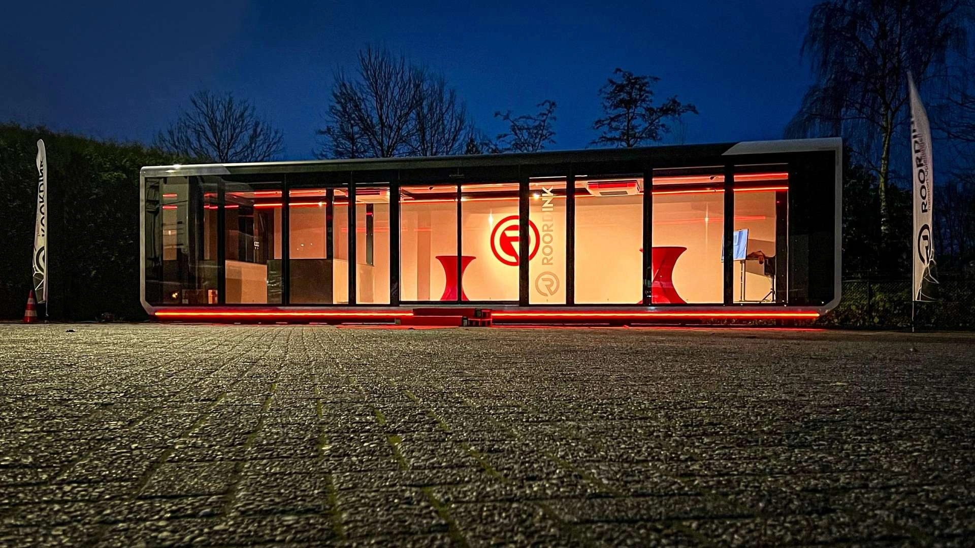 Roordink's Expandable training unit illuminated with red lighting at night, offering a modern, portable education space